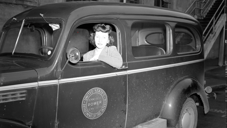 black and white image of woman sitting in BPA logo car, circa 1940
