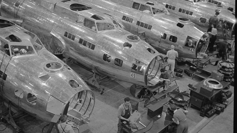 black and white photo showing people in an airplane factory, constructing B-17F Flying Fortress bombers at the Boeing aircraft plant in Seattle, Washington.