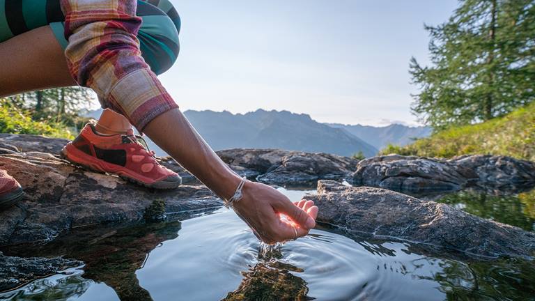 image of person cupping water on mountain