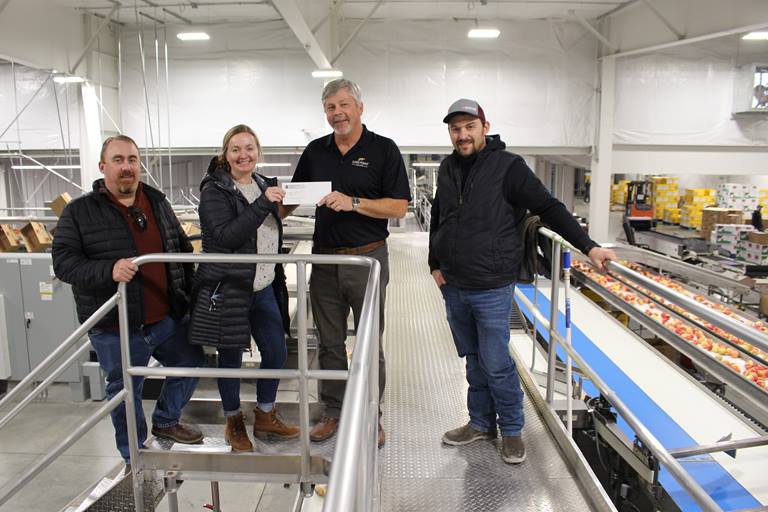 Energy Smart Industrial Partner Tony Simon; PUD Energy Services Coordinator Kim Johnson; Honeybear Growers general manager Jim Divis; and Honeybear Growers Production/Refrigeration Manager Ryan Moses gather in the upgraded facility to hand off the energy savings incentive check.