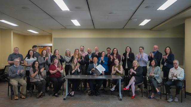 BPA Administrator John Hairston signs the Day-Ahead Markets Policy record of decision, joined by BPA staff and executives.
